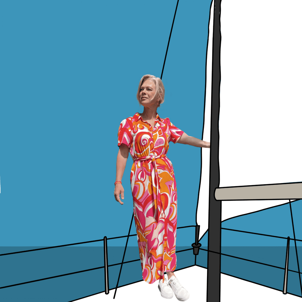 • Alt-tekst: Anne-Marije van Riet in kleurige retro maxijurk aan de mast van haar zeilboot, de blik kalm omhoog.